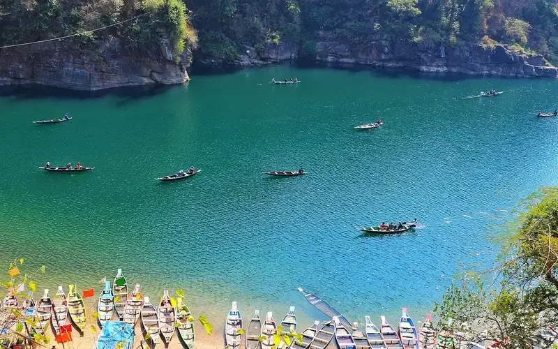 Misty hills, waterfalls, and lush green landscapes of Meghalaya under cloudy skies.