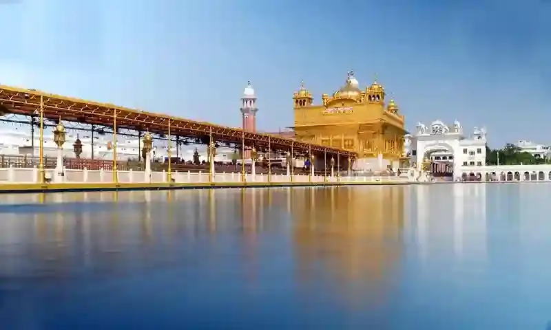 Golden Temple and surrounding water reflecting under clear skies in Punjab